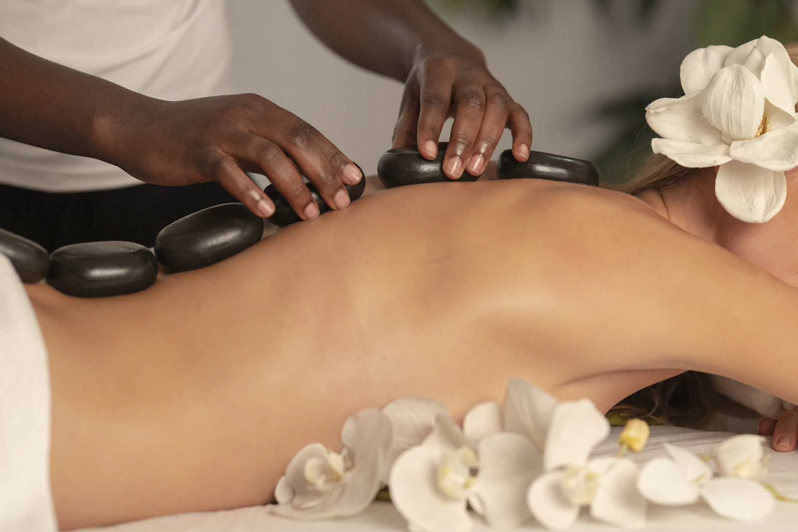 Piedras volcánicas calientes y orquídeas sobre la espalda en un masaje