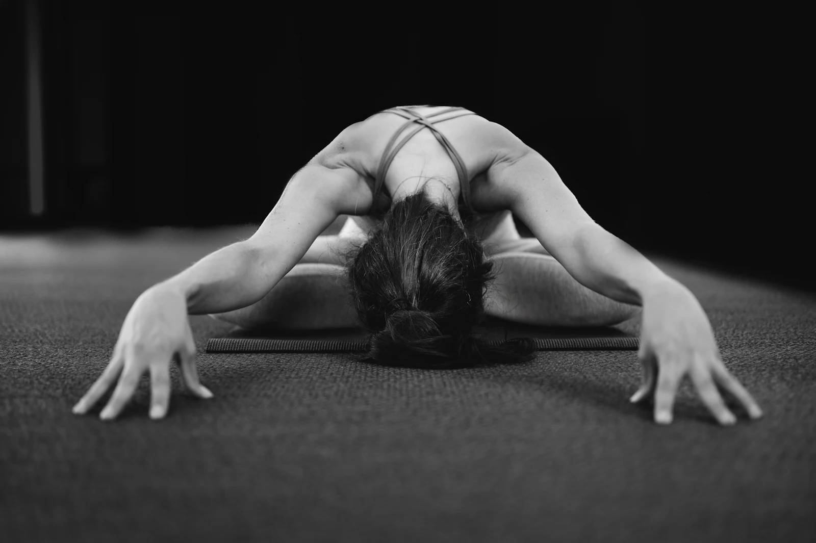 Persona estirando la espalda sobre una esterilla, en blanco y negro